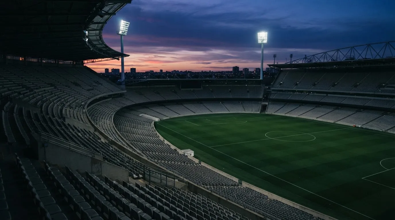 An empty football stadium with floodlight masts at dusk