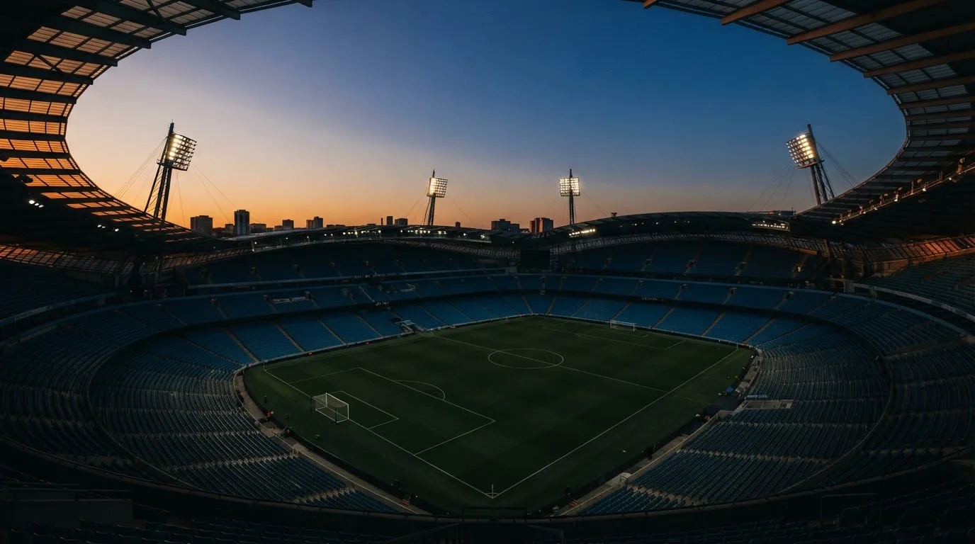 An empty football stadium with floodlight masts at dusk