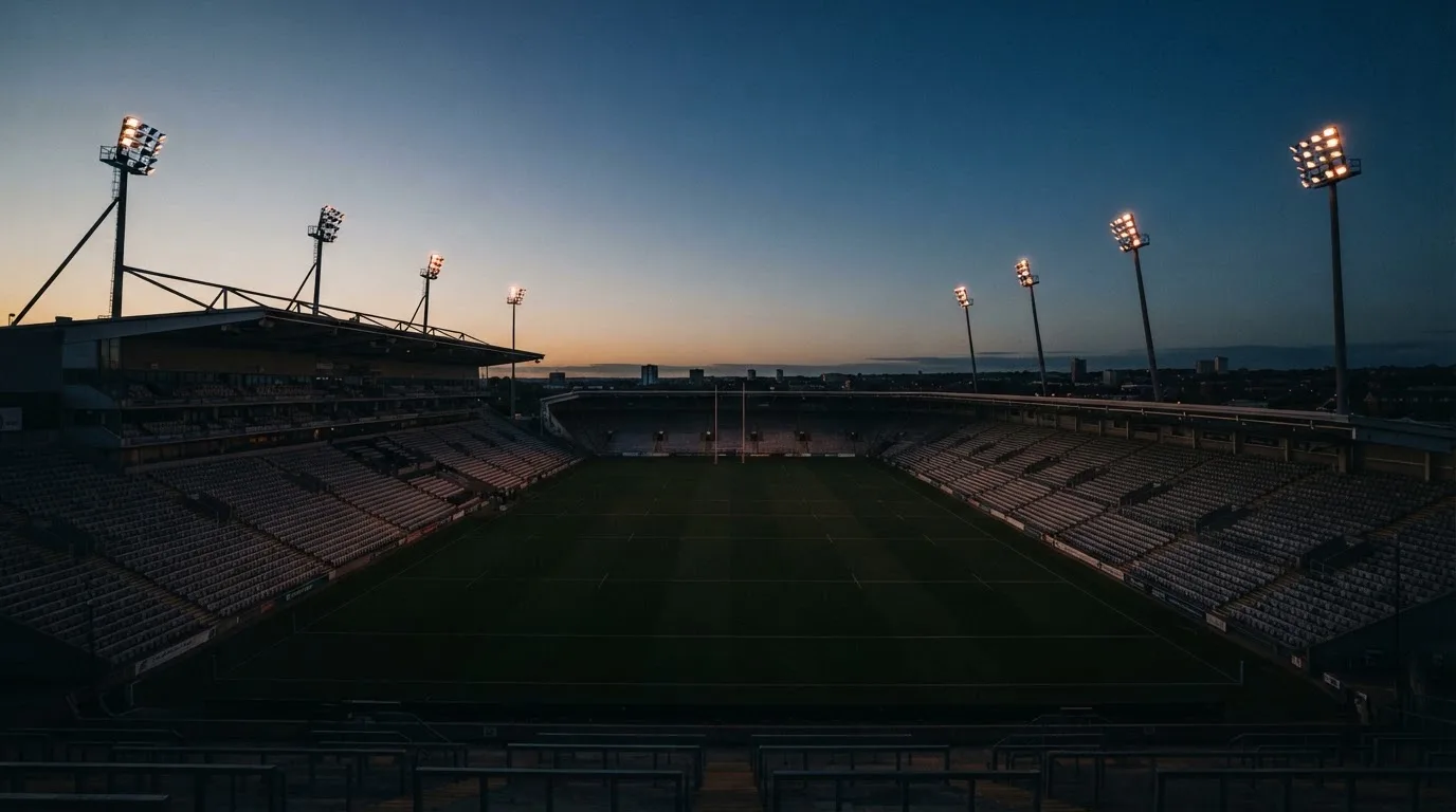 An empty football stadium with floodlight masts at dusk