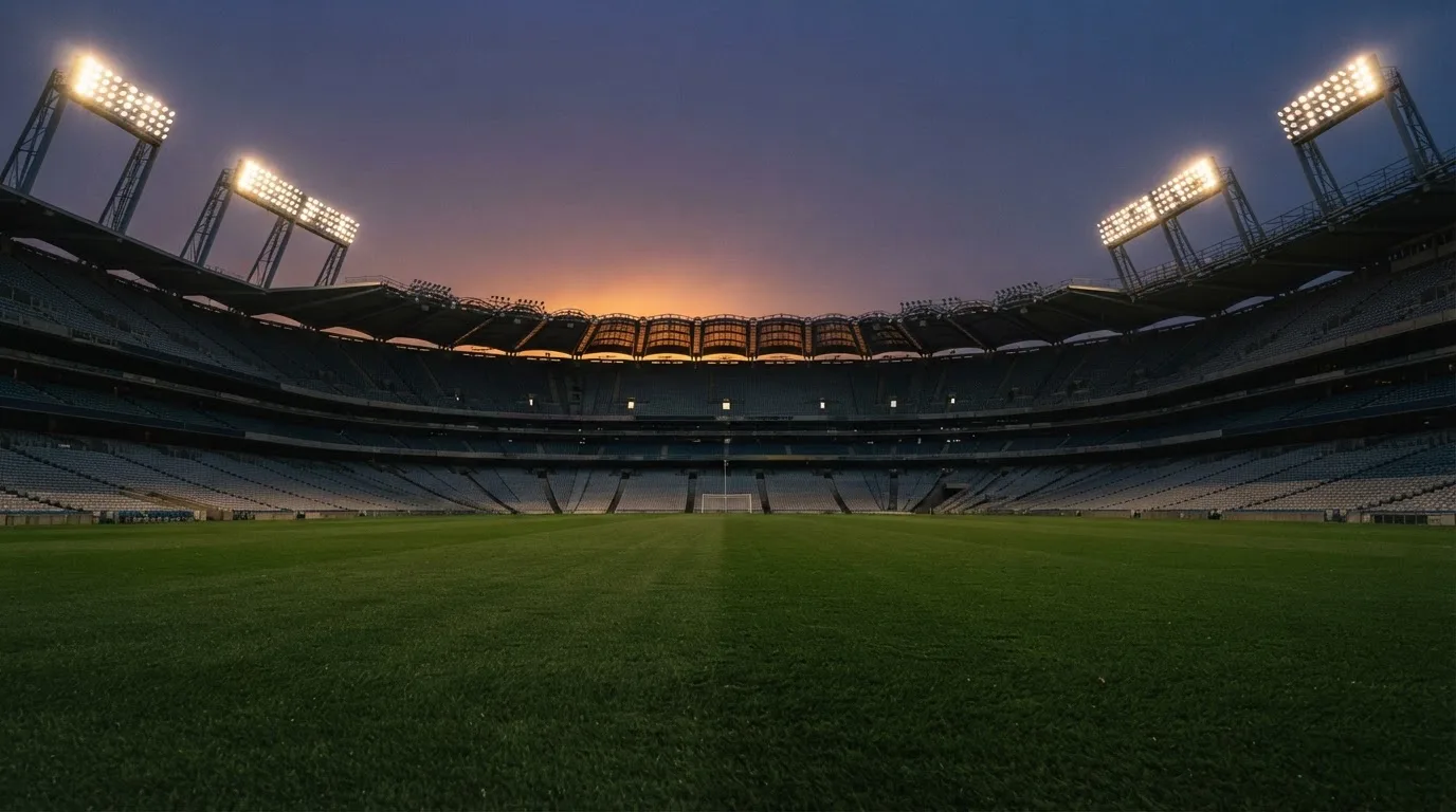 An empty football stadium with floodlight masts at dusk
