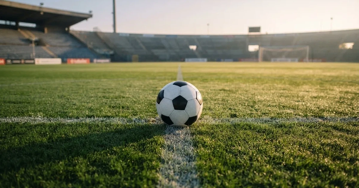 A ball on the centre spot of a grass pitch in morning light