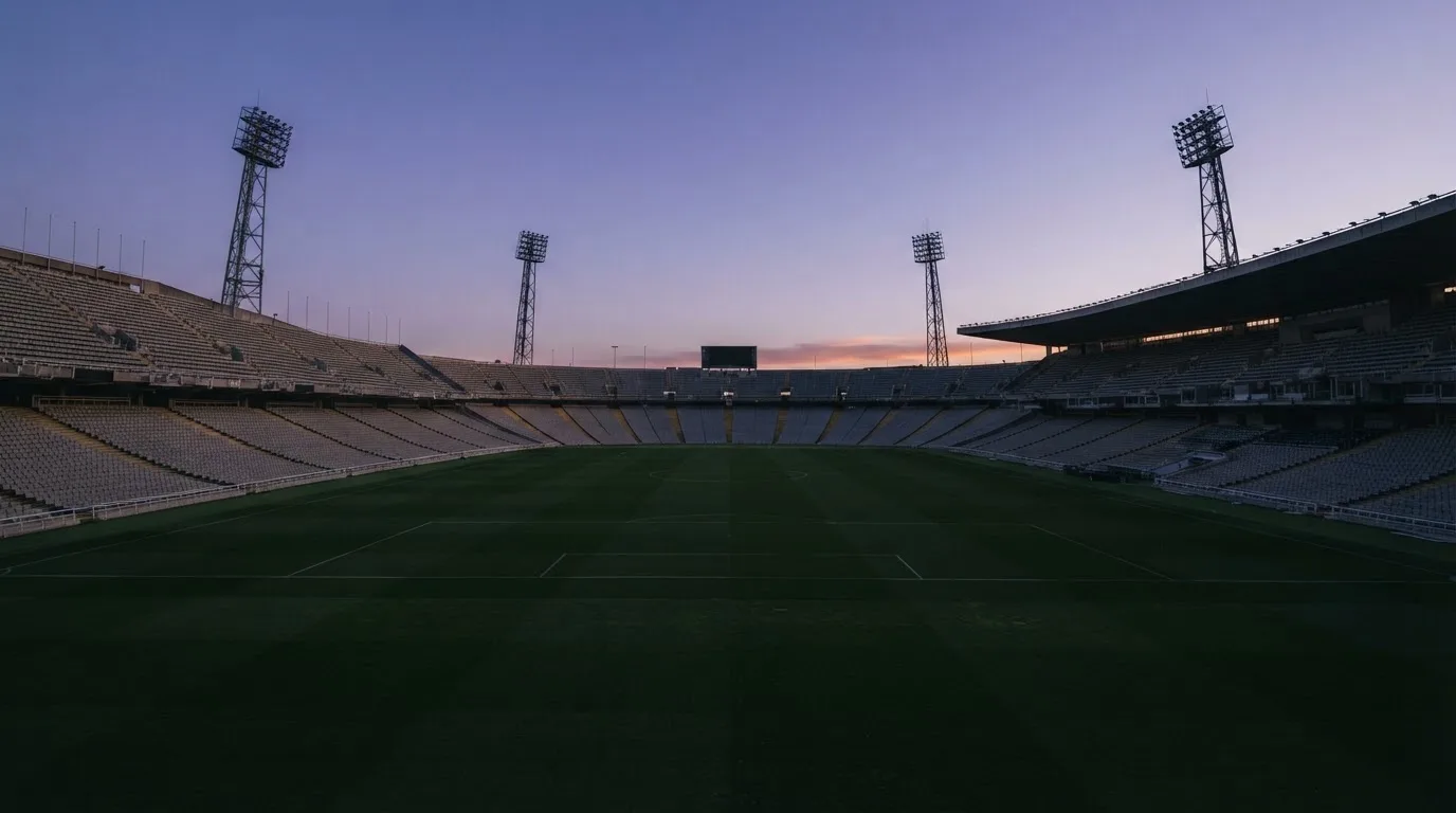 An empty football stadium with floodlight masts at dusk