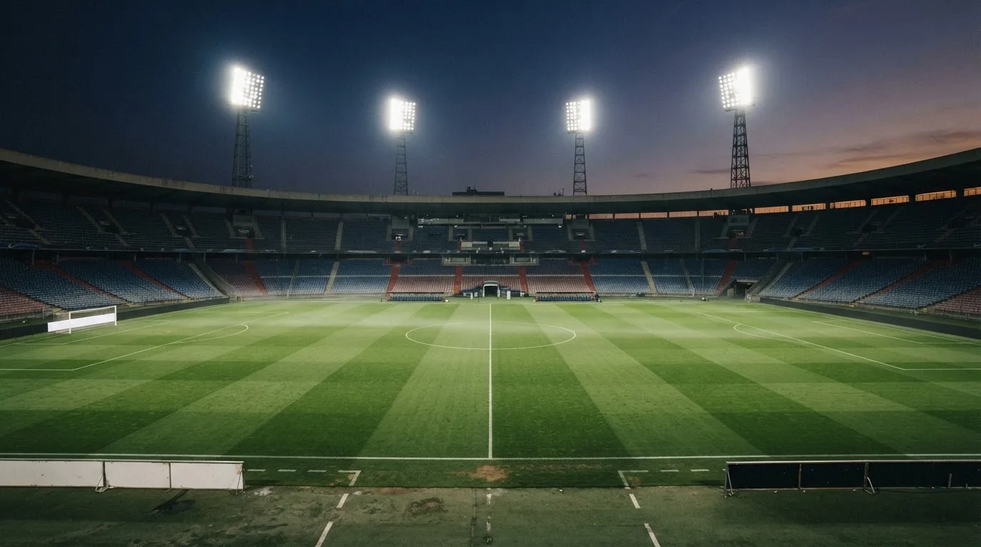 An empty football stadium with floodlight masts at dusk