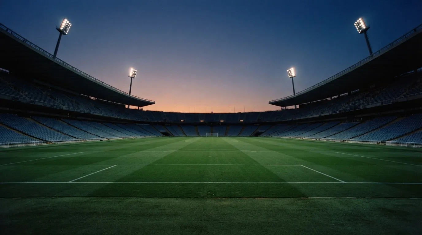 An empty football stadium with floodlight masts at dusk