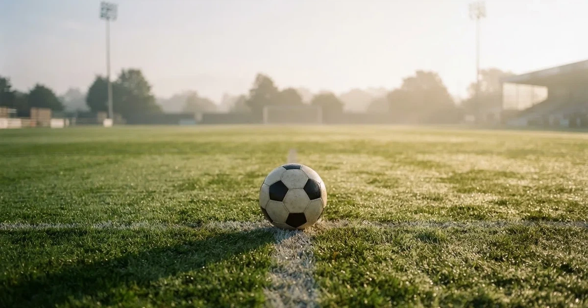 A ball on the centre spot of a grass pitch in morning light