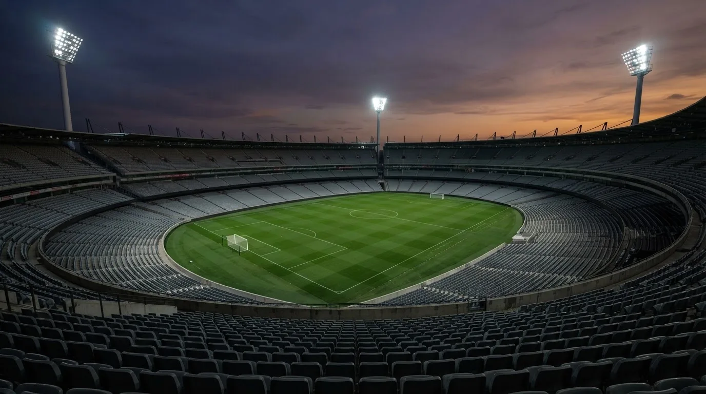 An empty football stadium with floodlight masts at dusk