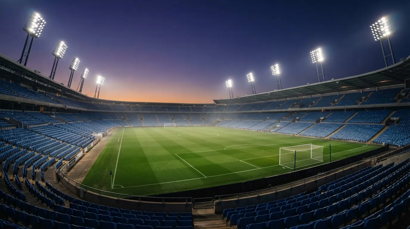 An empty football stadium with floodlight masts at dusk