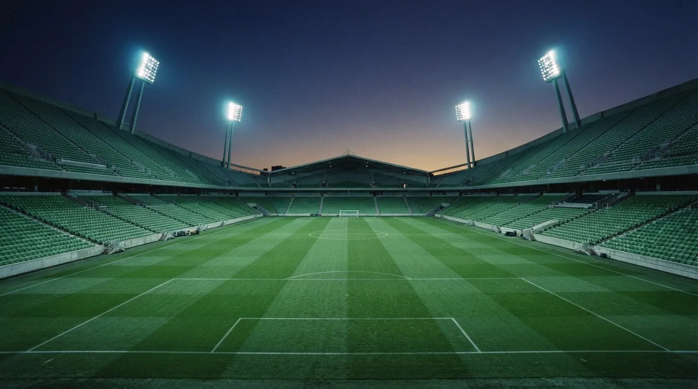 An empty football stadium with floodlight masts at dusk