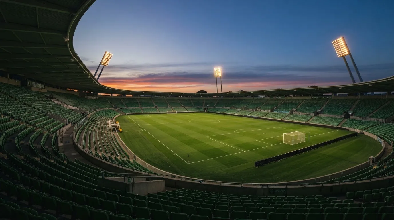 An empty football stadium with floodlight masts at dusk